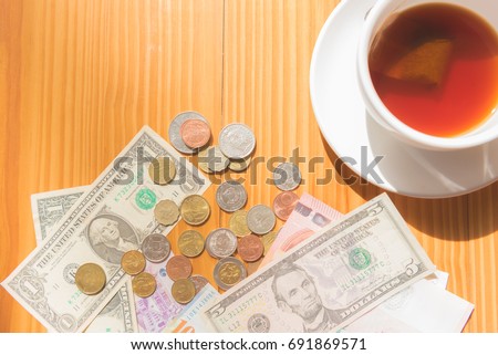 make money tip dollar or euro for travel and tea cup near on the wooden table