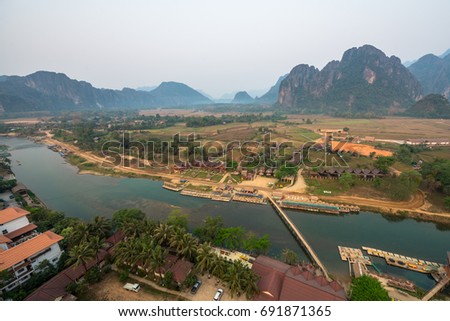 Horizontal picture of Nam Song River and hills in Vang Vieng from the top, inside the balloon in Laos, during sunrise time. Bamboo bridge.