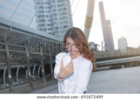 Front view of attractive young Asian woman taking a photo or selfie at urban city background.
