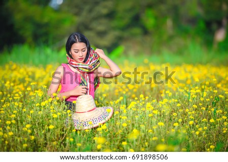Beautiful girl collects flowers in the field, in the evening on a sunset. A woman collects marigold flowers.