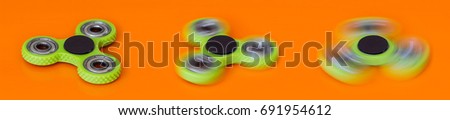 A set from three green hand spinner or fidget spinner on the orange background. Toys for stress relieving. Close up. Selective focus.