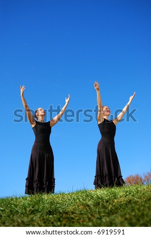 Ballerinas dressed in black performing outdoors in a bright day.