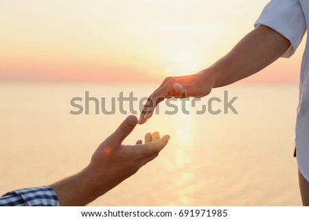 Lover boy makes an offer to his deushke on beach at sunrise (dawn). Creating a family. Creating a family. hands of the bride and groom on the background of sea close-up. Hand of support and help. 