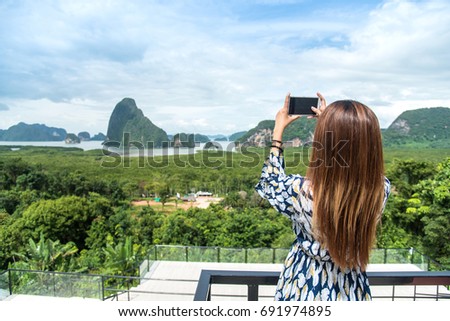 Women tourist he is shooting a beautiful scenic view by mobile phone at Phang Nga Bay, Samet Nang She Viewpoint,Thailand