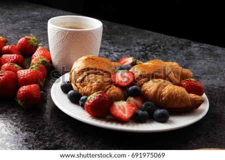 Delicious breakfast with fresh croissants and ripe berries on old marble background