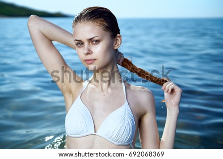 Woman straightens her hair wet in the sea                               