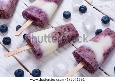 Ice yogurt popsicle with blueberries. On wooden background