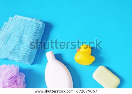 Blue cotton towel, purple sponge puff, white shampoo bottle, yellow rubber duck and baby soap. Flat lay stock photography. Bath products, natural cosmetic for body and hair care