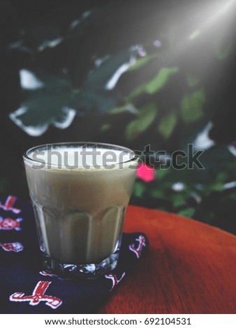 The picture of a cup of matcha latte on green tree background, while sunlight at  the morning