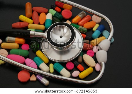 Colorful drugs and stethoscope on dark table