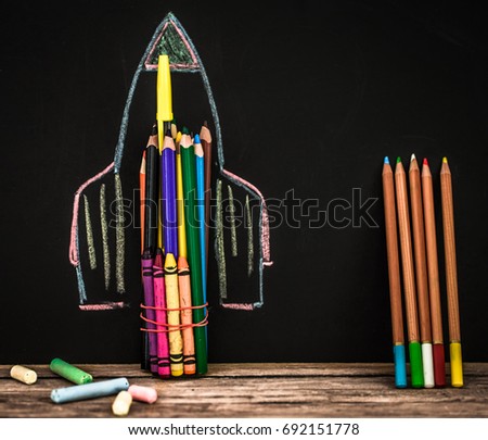 back to school rocket made out of pencils on a black background with school supplies on wooden background ,concept of education