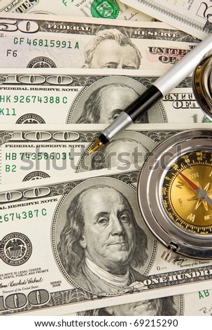 ink pen and gold compass on dollars