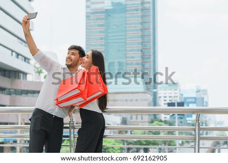 Man taking photo with beautiful woman holding shopping bags. Couple selfie having fun together. concept of photography with smartphone.