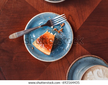 The remains of food on the table in the cafe, flat view. Mug with coffee and fork with a plate with crumbs from a cheesecake