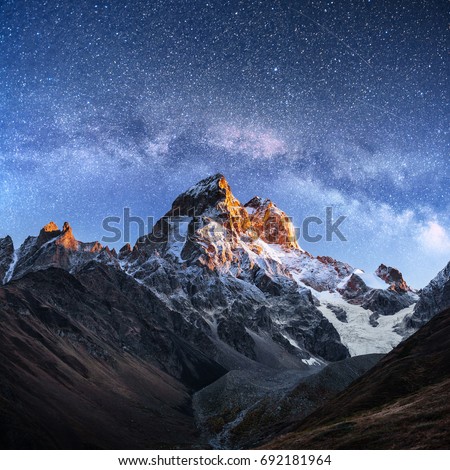 Fantastic starry sky. Autumn landscape and snow-capped peaks. Main Caucasian Ridge. Mountain View from Mount Ushba Meyer, Georgia. Europe. Royalty-Free Stock Photo #692181964