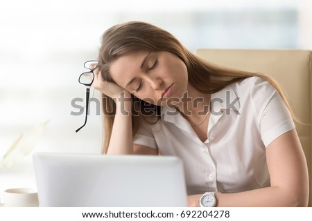 Bored sleepy businesswoman sitting half asleep at workplace, lazy woman disinterested in boring routine, tired employee dozing on hand during break, falling asleep at desk, lack of sleep, head shot Royalty-Free Stock Photo #692204278