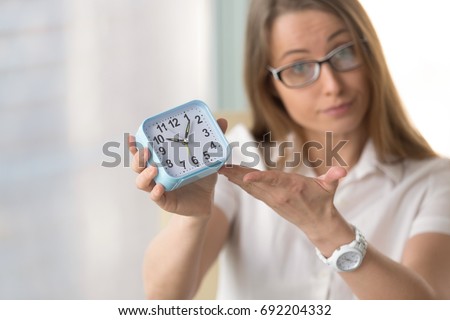 Waiting woman pointing at time, urging to hurry, warning not being late or miss appointment, meeting deadline, finish project due date, focus on clock, time management and punctuality at work concept Royalty-Free Stock Photo #692204332
