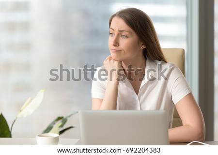 Discontented thoughtful woman with hand under chin bored at work, looking away sitting near laptop, demotivated office worker feels lack of inspiration, no motivation, boring routine, creative crisis Royalty-Free Stock Photo #692204383