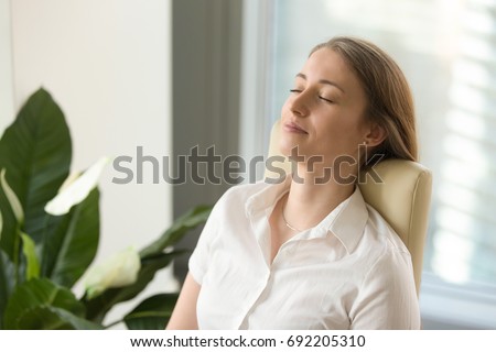 Calm attractive woman feeling relaxed in office home, peaceful mindful businesswoman leaning back on chair with eyes closed, meditating at work, taking deep breath to relax, no stress at workplace Royalty-Free Stock Photo #692205310
