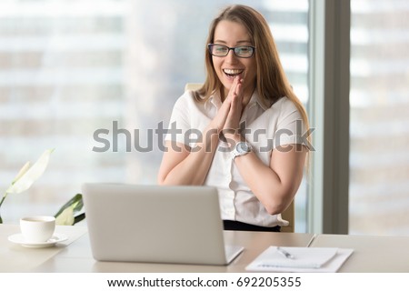 Happy businesswoman laughing with joy at workplace, gladly looking at laptop screen, feeling excited about online win, watching funny video on computer, enjoying positive good news in internet Royalty-Free Stock Photo #692205355