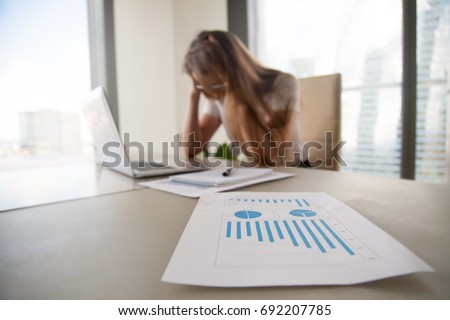 Depressed frustrated businesswoman holding head in hands, female boss shocked by decreasing sales in documents, focus on falling stats, profit loss graphs, company bankruptcy or financial problems Royalty-Free Stock Photo #692207785