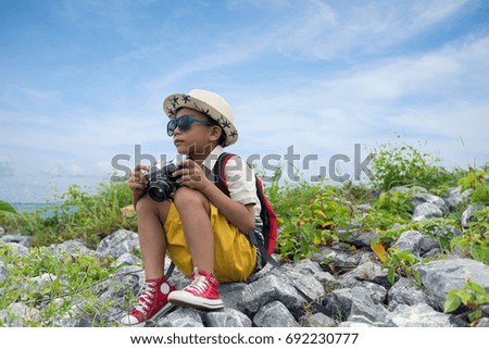 asian boy in hat with retro photo camera on the blue cloudy sky