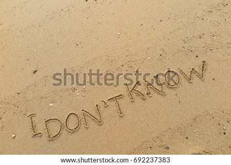 Handwriting  words "I DON'T KNOW" on sand of beach.