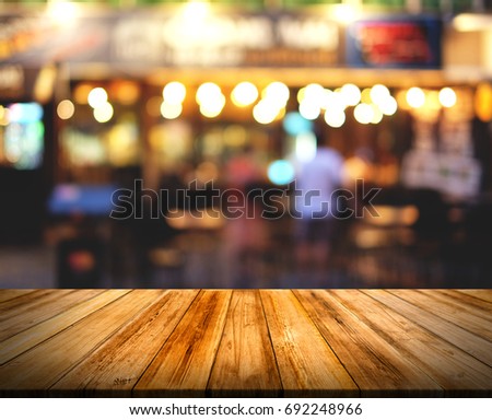 The image of a brown wood table in front of the background blurred. There is a bokeh of light.