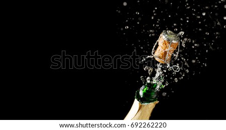 Opening bottle of champagne on empty black background