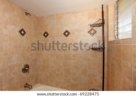 Beige stone tile shower with white tub