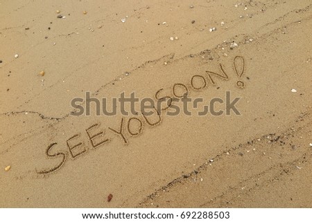 Handwriting  words "SEE YOU SOON!" on sand of beach. Royalty-Free Stock Photo #692288503