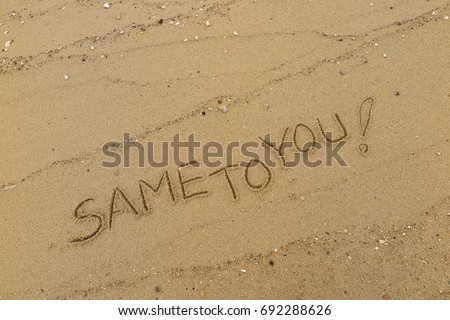 Handwriting  words "SAME TO YOU!" on sand of beach.