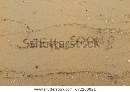 Handwriting  words "SEE YOU SOON!" on sand of beach. Royalty-Free Stock Photo #692288821