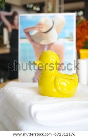 Yellow duck made from ceramic, sitting on the white towel, soft focus