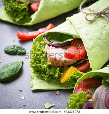 Green spinach tortilla with Chicken and vegetables. Healthy snack. Close up.