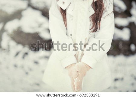 Little girl in the white coat walking on the winter street with first snow 