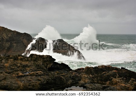 Giant Waves Nature Show crashing against dark colored cliffs, Meirás, A coruna, Galicia, Spain, raising a white foam dozens of meters against sky with stormy gray clouds in a dark green atlantic ocean
