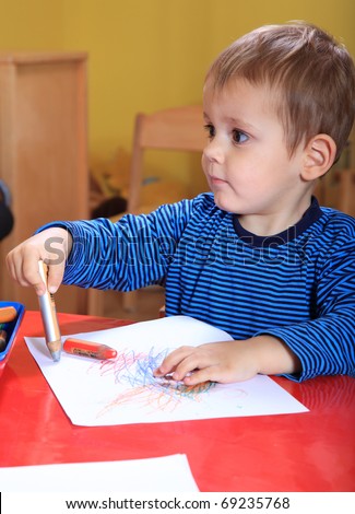 Cute caucasian toddler drawing a picture in kindergarten.