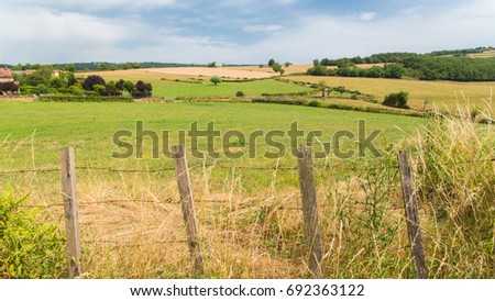      Wooden barrier  in a field, white cows, campaign in France 