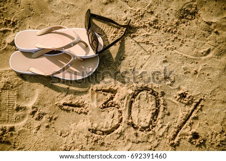 20 lettering written on sand. Summer beach background