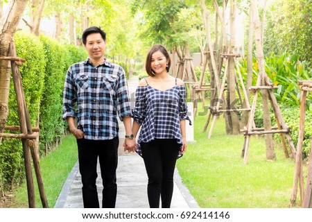 Portrait of lovely couple: A handsome man is holding his beautiful girlfriend and they are so happy. They are walking around the beautiful park
