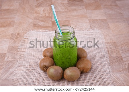 A homemade kiwi smoothie for vegan breakfast on a white fabric and on a wooden background. Healthful ingredients.