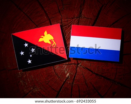 Papua New Guinea flag with Dutch flag on a tree stump isolated