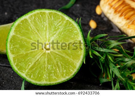 Macro picture of cut sour lime and raw melon seeds on a black background. Delicious bright fruits with tarragon herbs.