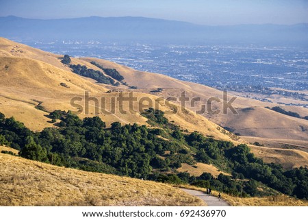 Trail through the golden hills of Mission Peak preserve; downtown San Jose in the background, south San Francisco bay, California