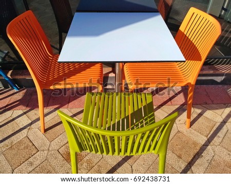 Multicolored plastic table and chairs. Restaurant furniture in the open sun. Minimalistic composition, laconic, bright shades