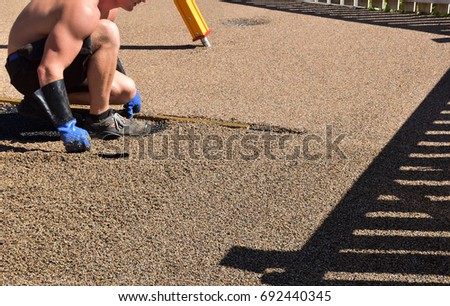 Man working on playground Rubber beads floor. Shredded and cut pieces of used recycled rubber tire crumb reused soft surface ground floor filler mulch compound on safety and injury prevention 