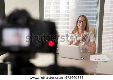 Smiling businesswoman talking on camera, happy entrepreneur vlogger recording business vlog at office desk for videoblog, filming promo ad, making presentation to website, video marketing production Royalty-Free Stock Photo #692440666