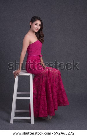 Young Asian & beauty woman in a fashionable dress red.  with chair. Gray background