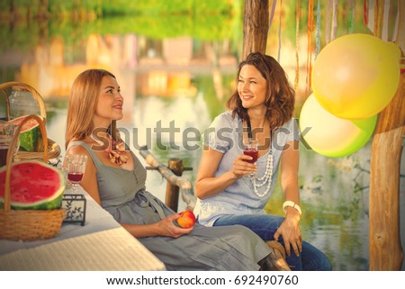 Two beautiful cheerful women at a party with wine and watermelons. instagram image filter retro style